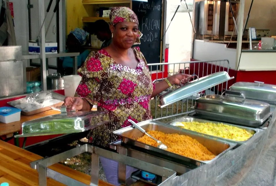 Adesuwa achter een buffet met warmhoudbakken