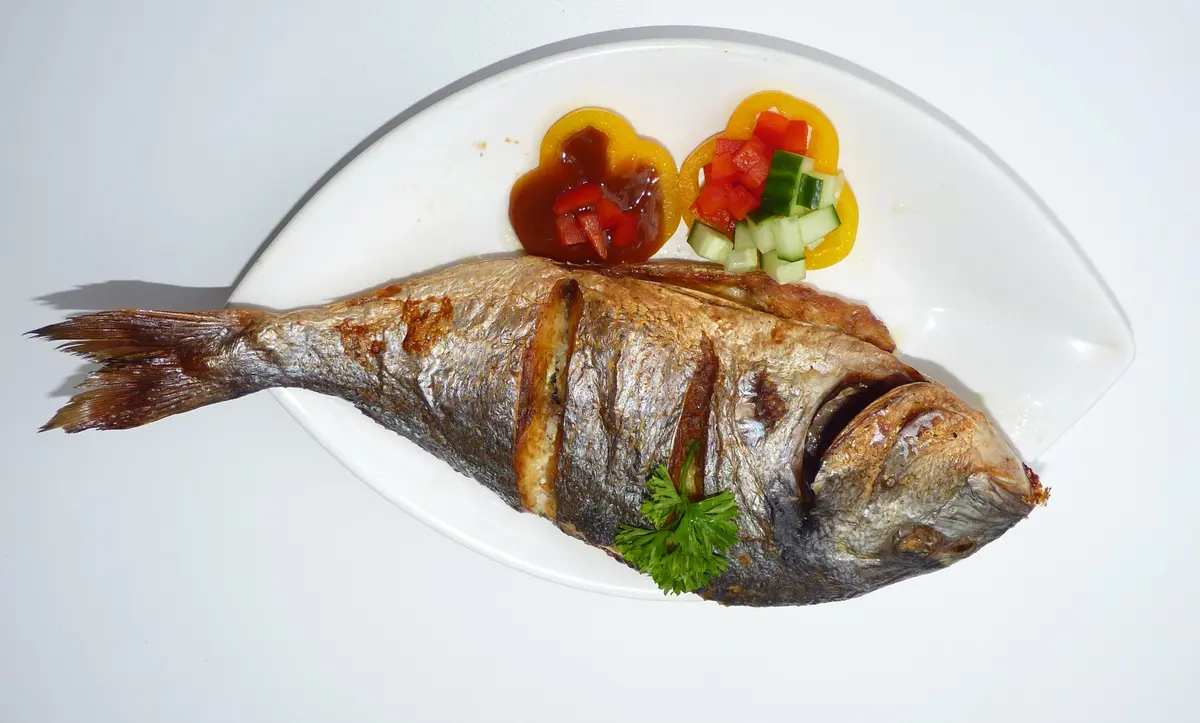 Een hele gegrilde vis op een wit bord