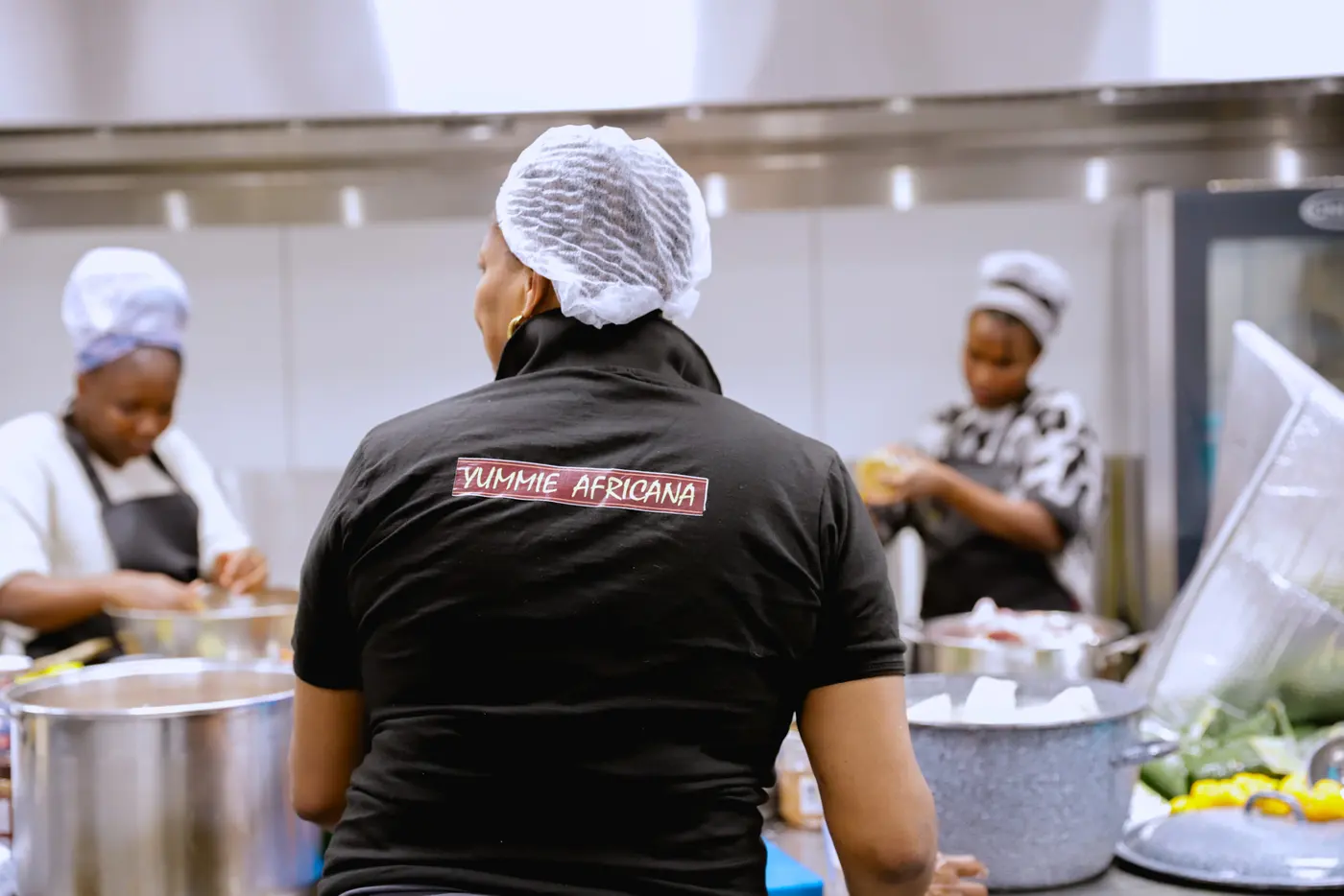 Het keukenteam aan het werk, een van hen in een zwart Yummie-Africana-shirt